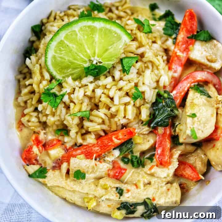 Thai coconut lime chicken with red bell pepper slices and lime slices over rice in a bowl.