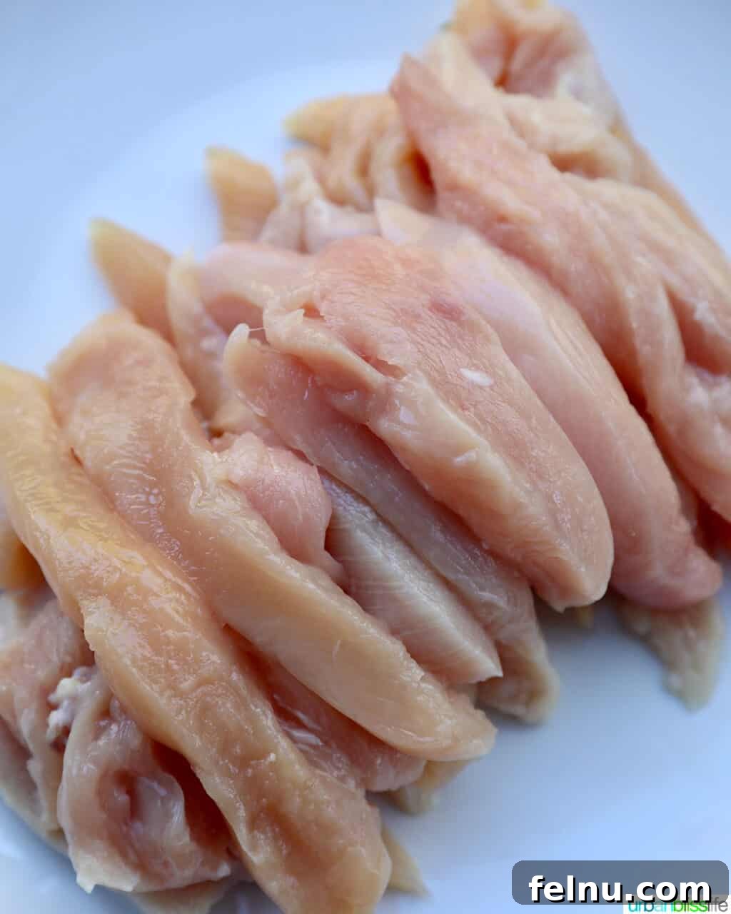 Tropical Coconut Lime Chicken 5 Thinly sliced raw chicken breast, seasoned and ready for cooking in a skillet.