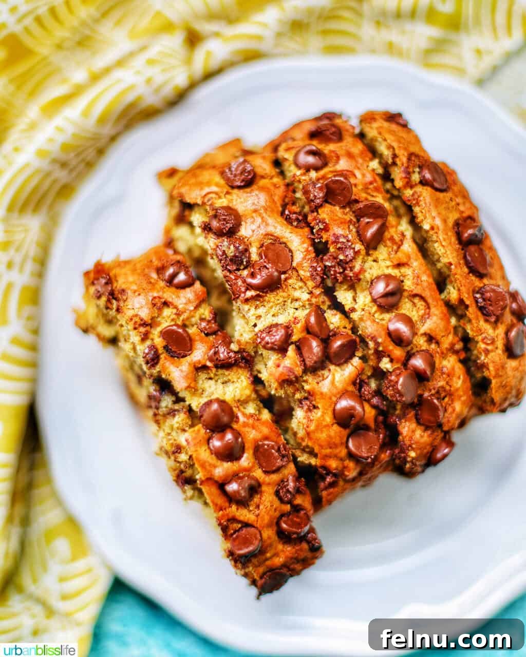 Effortless Chocolate Chunk Banana Bread 4 Slices of warm chocolate chip banana bread served on a white plate with a delicate yellow napkin.