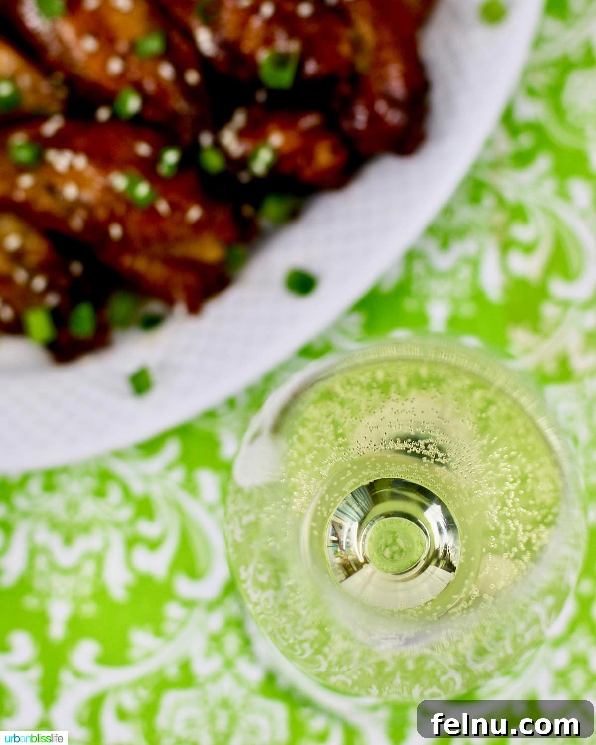 Sip, Sizzle, Savor: Wines That Perfect Your BBQ 16 A pristine glass of Riesling white wine positioned elegantly next to a plate of savory Asian chicken wings.