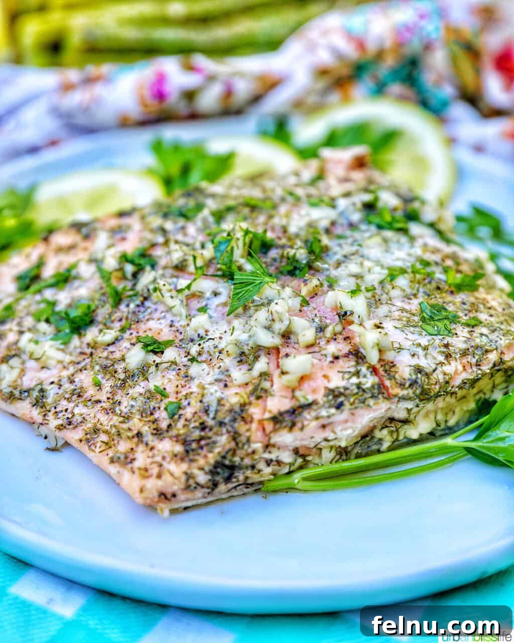 Zesty Lemon Herb Salmon Delight 12 Side view of grilled salmon with herbs and lemon slices on a white plate.