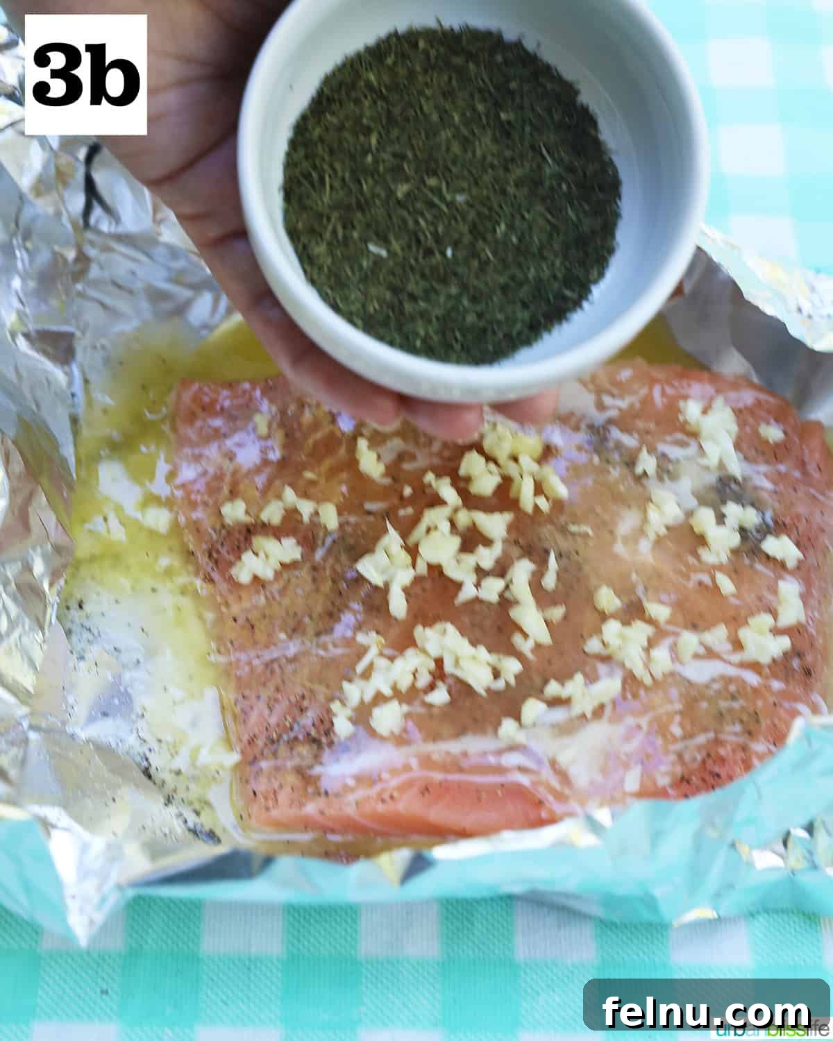 Zesty Lemon Herb Salmon Delight 8 Dill being poured onto salmon and garlic in foil.