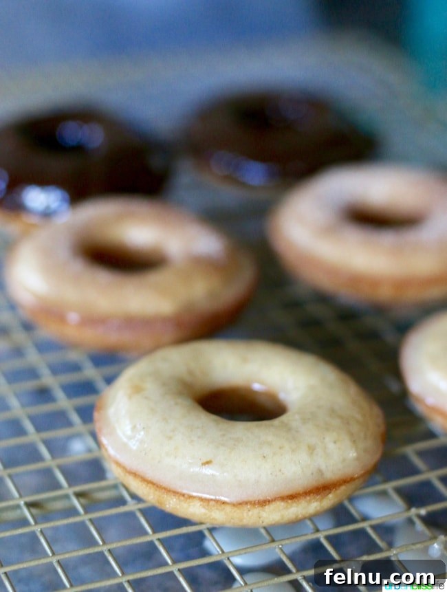 Freshly glazed cinnamon sugar donuts cooling on a rack.