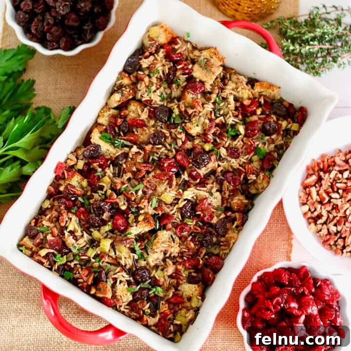 A Festive Harvest Stuffing 8 Cranberry stuffing with wild rice and cherries in a casserole dish with bowls of cherries and herbs on the side.