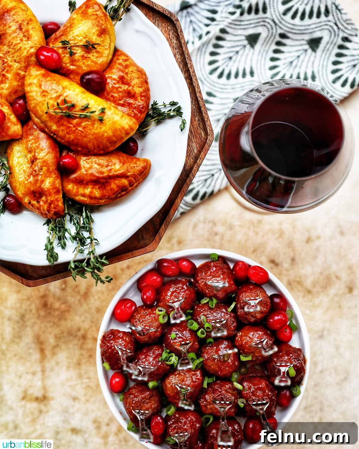 Sweet and Tangy Cranberry Glazed Meatballs 16 holiday appetizers of cranberry meatballs, mushroom empanadas, and glass of red wine on a festive table