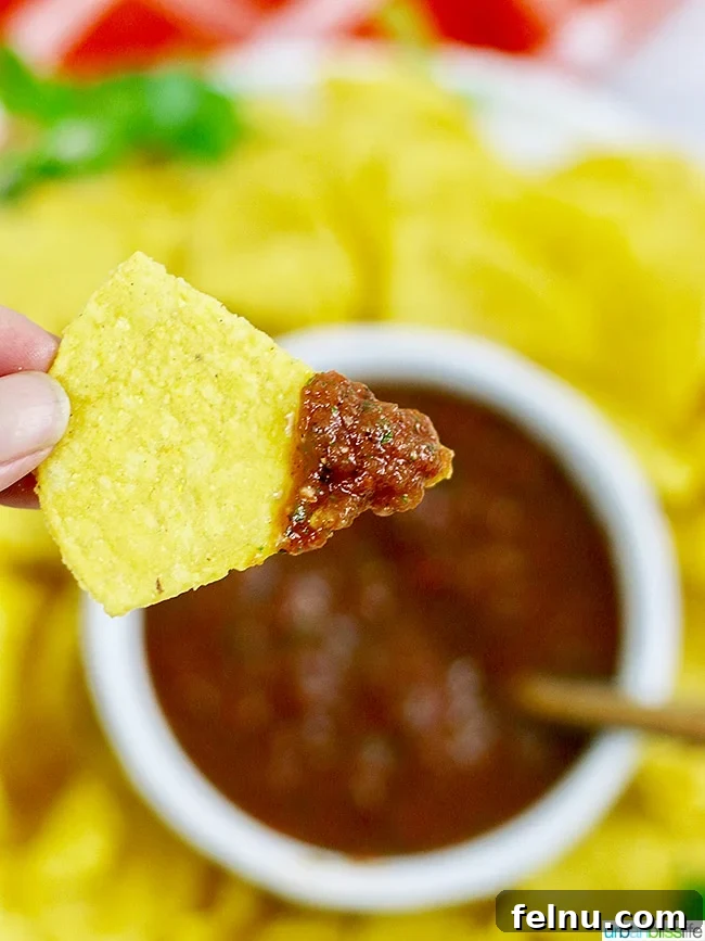 Hand dipping a chip into a bowl of restaurant-style salsa