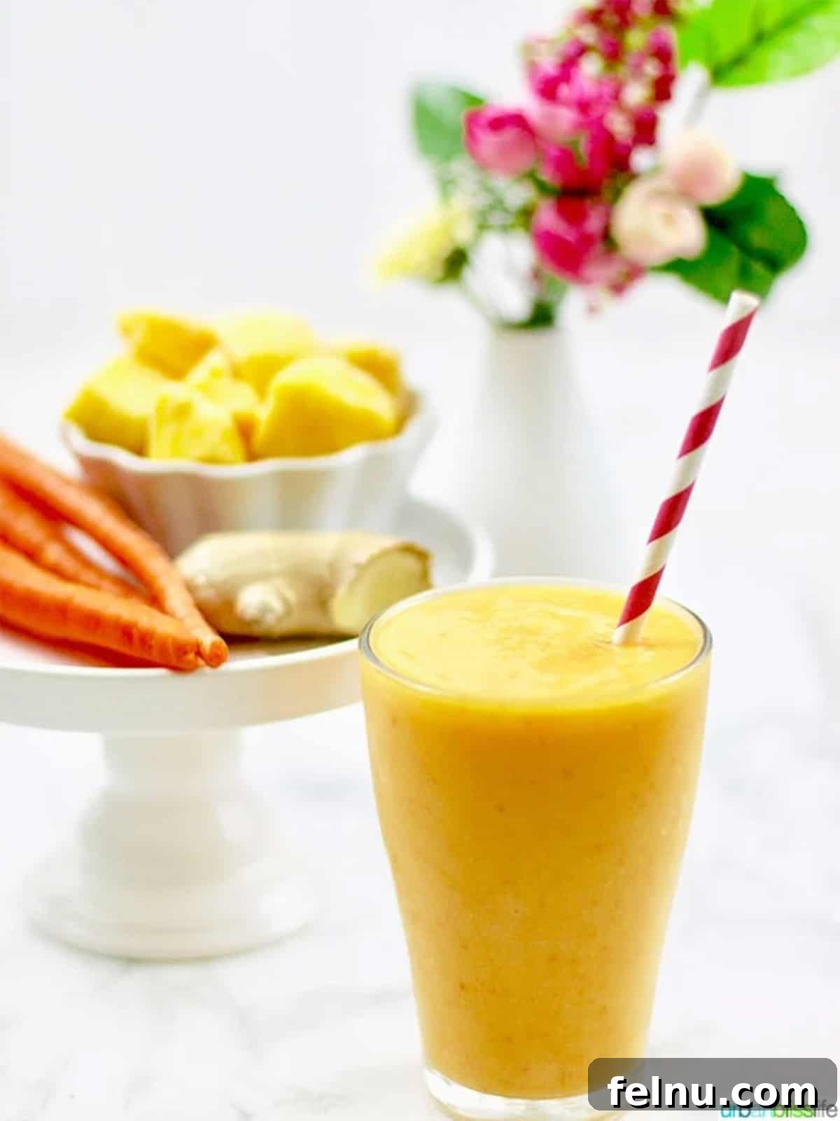 Mango Carrot Elixir 4 Close-up of mango carrot smoothie in a glass with straw
