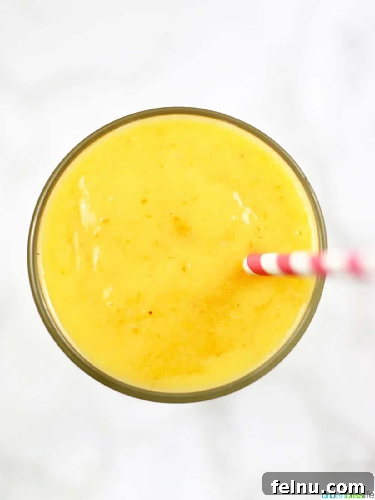 Mango Carrot Elixir 5 Overhead shot of mango carrot smoothie in a glass with a straw