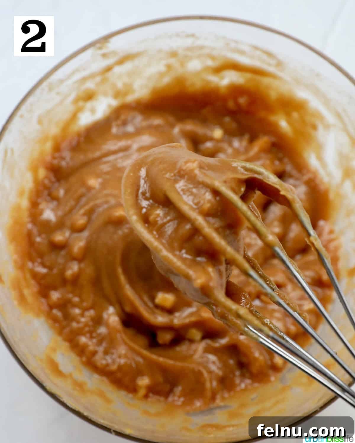 Effortless Homemade Thai Peanut Sauce 6 whisk in a bowl with homemade peanut sauce.