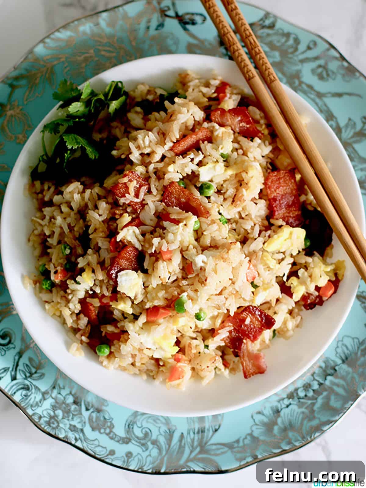 Filipino Fried Rice Your Choice of Bacon or Sausage 5 Filipino Fried Rice with sausage, garnished with fresh herbs in a large pan.