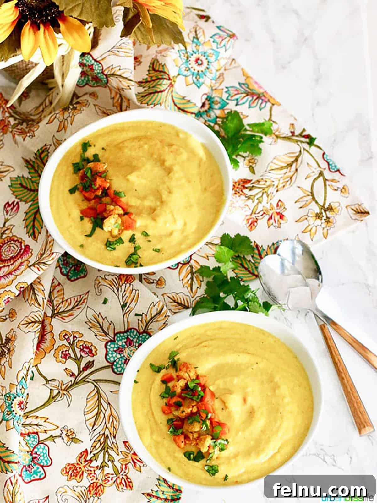Golden Carrot Cauliflower Puree 3 Two pristine white bowls showcasing the delicious Cauliflower Carrot Soup, generously topped with an artful sprinkle of finely chopped cauliflower, delicate carrot shreds, and vibrant green parsley. The arrangement highlights the soup's fresh ingredients and appealing presentation.