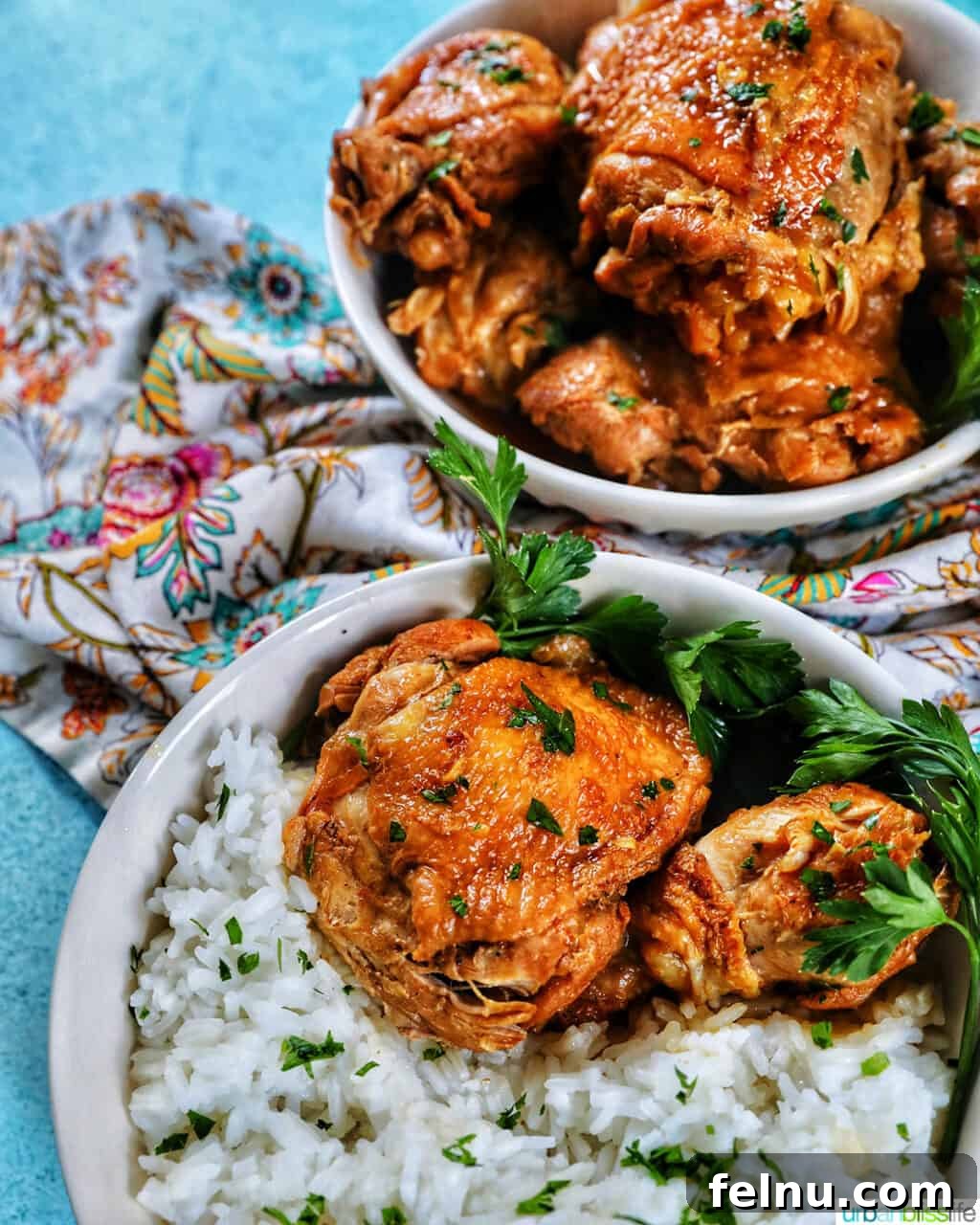 Ultimate Instant Pot Chicken Adobo 16 two bowls of Instant Pot Filipino Chicken Adobo and rice, with a colorful floral napkin and forks.