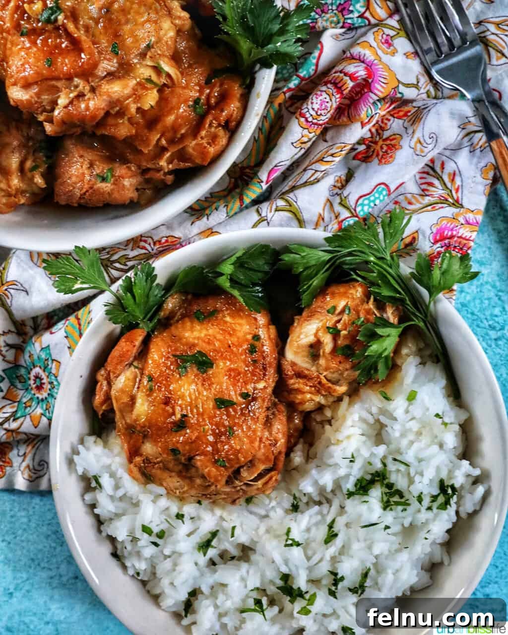 Ultimate Instant Pot Chicken Adobo 3 two bowls of Instant Pot Filipino Chicken Adobo and rice, with a colorful floral napkin and forks.