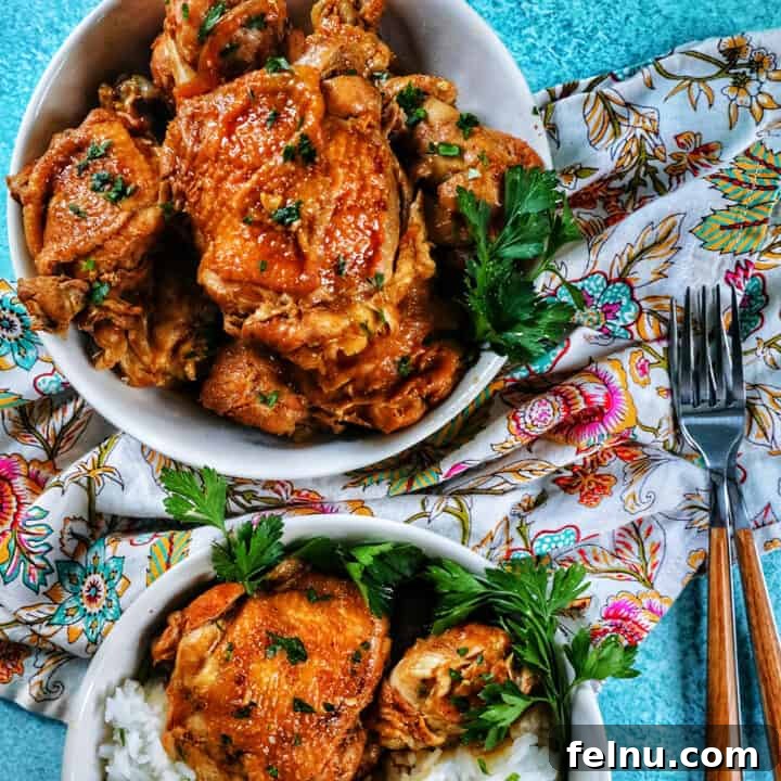 two bowls of Instant Pot Filipino Chicken Adobo and rice, with a colorful floral napkin and forks.