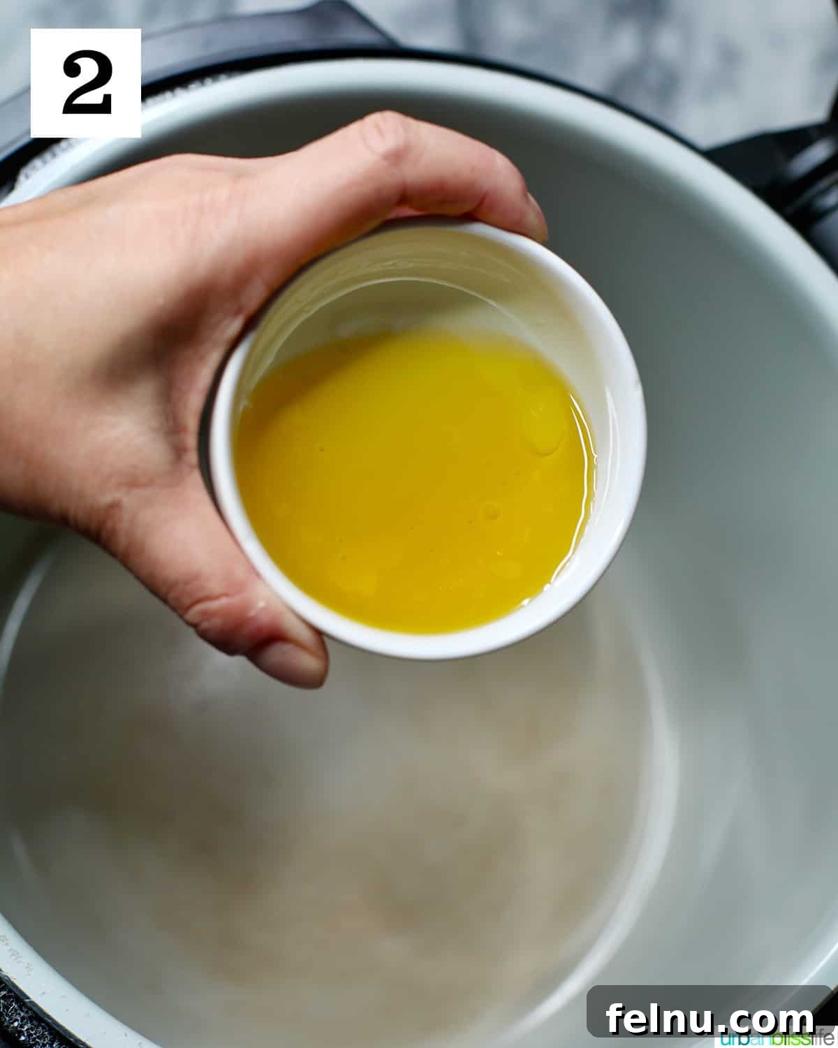 Ultimate Instant Pot Chicken Adobo 6 hand holding bowl of olive oil pouring into pot of a Ninja Foodi pressure cooker