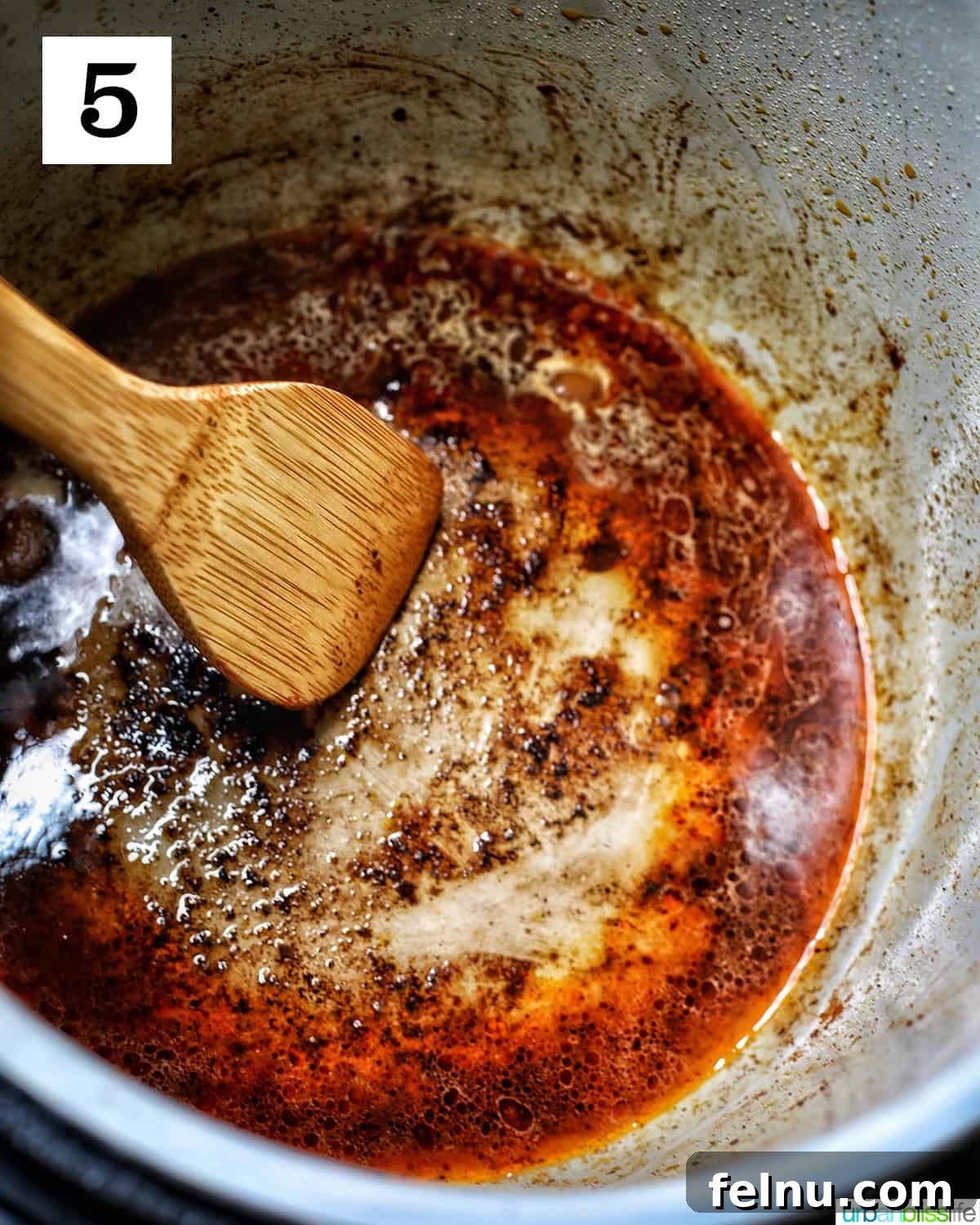 Ultimate Instant Pot Chicken Adobo 10 wooden spoon scraping up brown bits deglazing an instant pot with broth.
