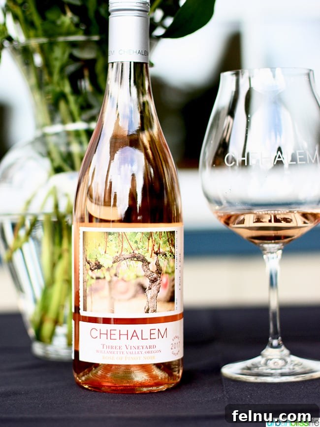 Chehalem Winery and Hi-Lo Hotel Present Hi-Lo Cuvée Wines 6 A glass of elegant rosé wine beside a bottle, showcasing its light salmon color