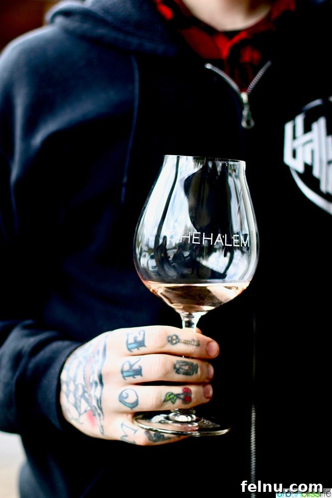 Chehalem Winery and Hi-Lo Hotel Present Hi-Lo Cuvée Wines 7 A person holding a glass of Chehalem Winery rosé, revealing arm tattoos