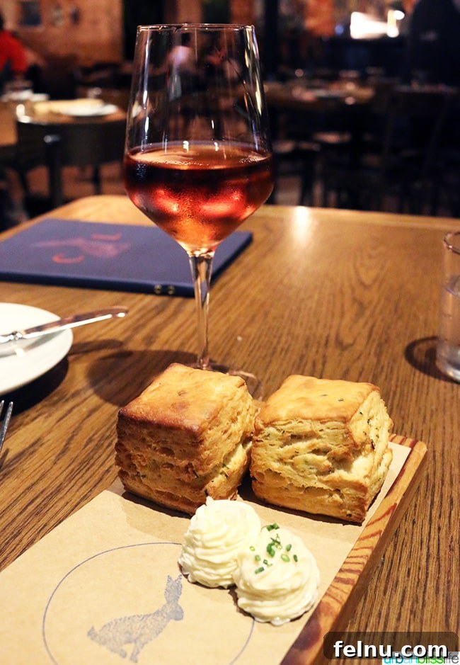 Where Caribbean Spice Meets Creole Soul at Compère Lapin New Orleans 7 A glass of rosé wine next to a plate of famous square biscuits with butter at Compere Lapin.