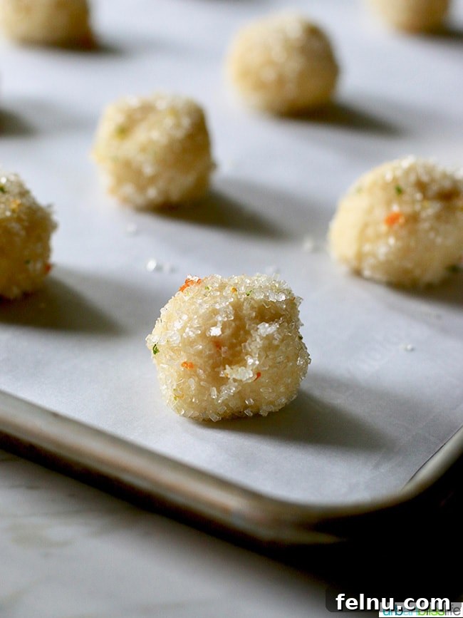 Triple Citrus Sugar Cookies 4 Raw citrus sugar cookie dough balls ready for baking on parchment paper.