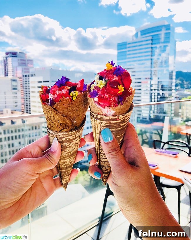 Cool Summer Dairy-Free Ice Cream at Departure Portland 9 Two exquisitely plated scoops of dairy-free coconut ice cream with fermented berry swirl, garnished with edible flowers and gold leaf, on custom vegan cones.