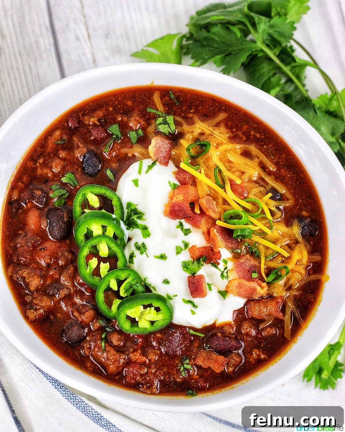 Hearty & Healthy Turkey Chili (Instant Pot Friendly!) 3 An inviting bowl of Instant Pot Turkey Chili with vibrant toppings like jalapenos, sour cream, crispy bacon, and cheddar cheese, garnished with fresh green herbs on the side.