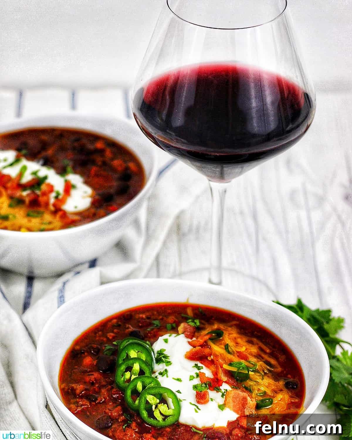 Hearty & Healthy Turkey Chili (Instant Pot Friendly!) 23 Two bowls of chili served with a glass of red wine, creating a perfect pairing for a cozy meal.