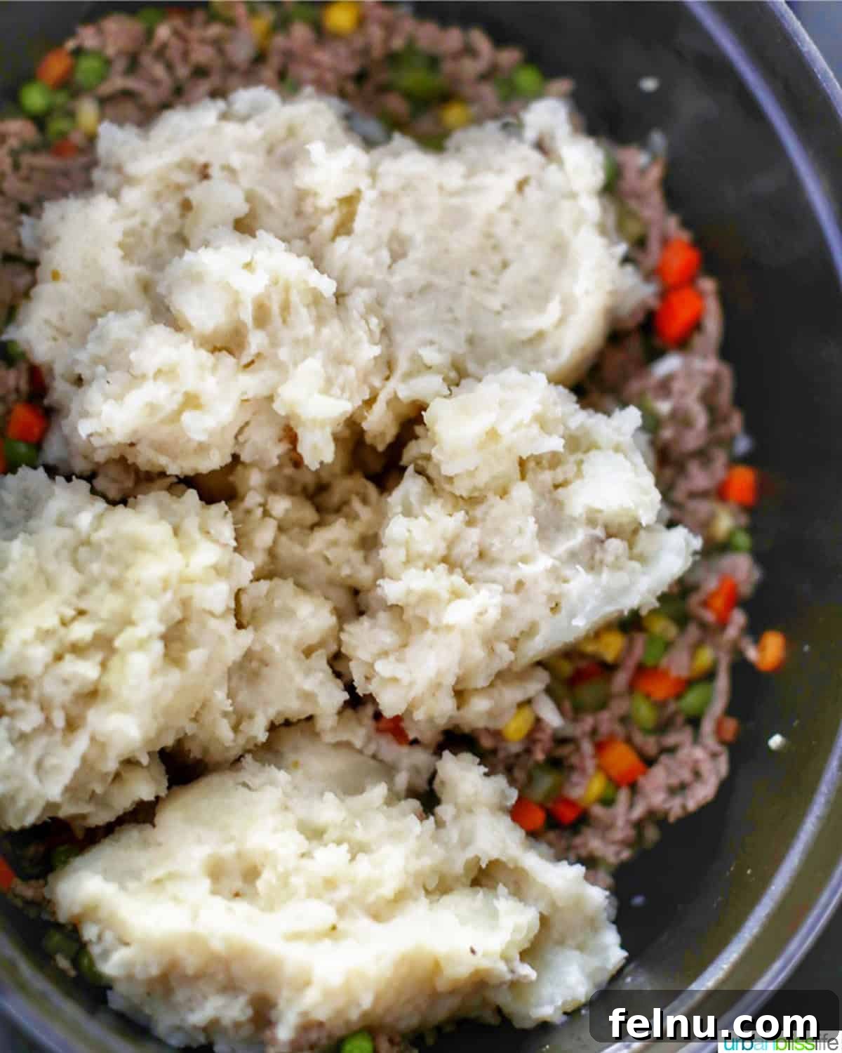 Hearty Dutch Oven Shepherd's Pie 3 Adding potatoes to the Dutch Oven Shepherd's Pie filling.