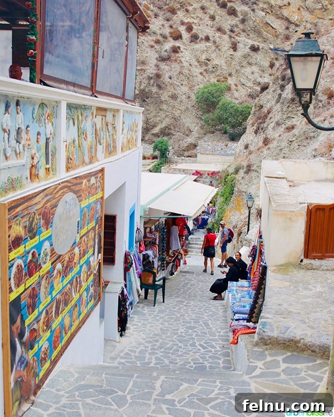 Greece Travel: Discover Olympos Village, Karpathos 15 A cobblestone street in Olympos, Karpathos, with a restaurant and a clothing shop
