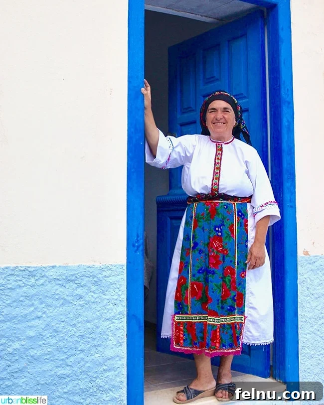Greece Travel: Discover Olympos Village, Karpathos 10 A Karpathian woman in traditional dress standing in a doorway in Olympos, Greece