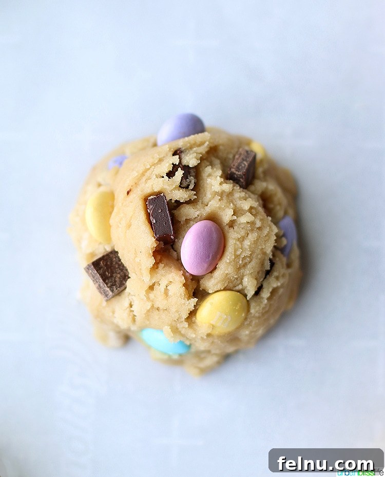 Colossal Chocolate Chunk Cookies 6 Giant Chocolate Chip M&M Cookie dough, highlighting the generous amount of chocolate and M&Ms mixed in.