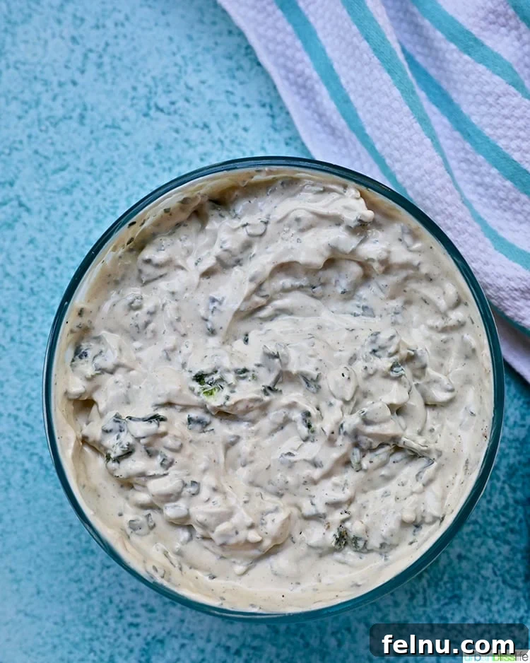 Effortless Creamy Spinach Dip (Dairy-Free) 3 A bowl of dairy-free spinach dip surrounded by crackers and vegetables