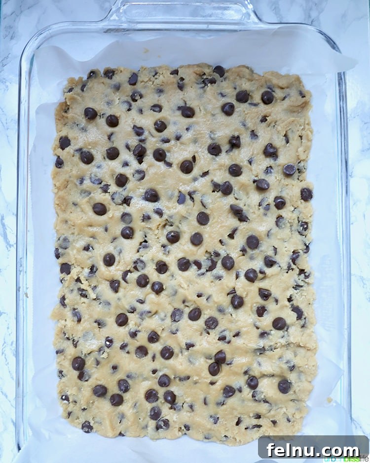 Pouring the chocolate chip bar mixture into a prepared pan.