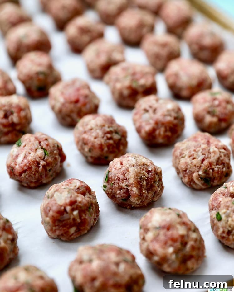 Tangy Romesco Meatballs 3 Meatballs baking on a sheet pan, ready to be served with Romesco Sauce.