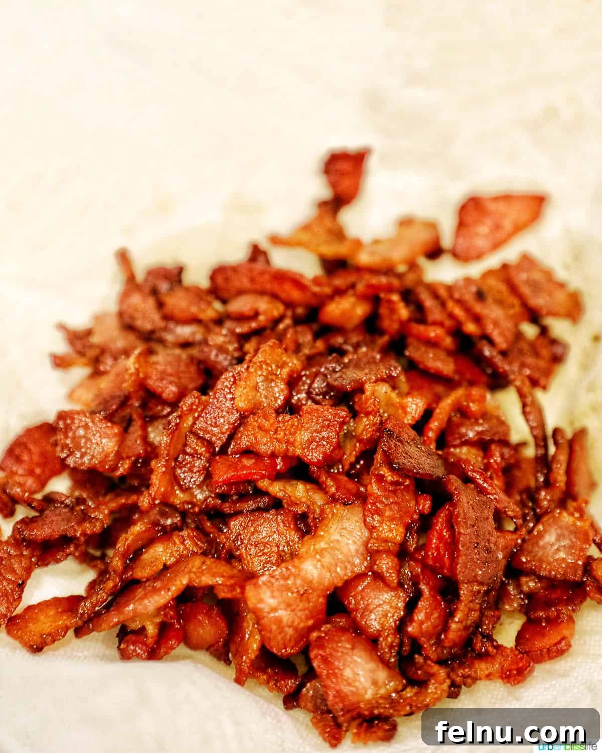 Creamy Kaleidoscope Corn 6 crispy cooked bacon draining fat on a paper towel lined plate.