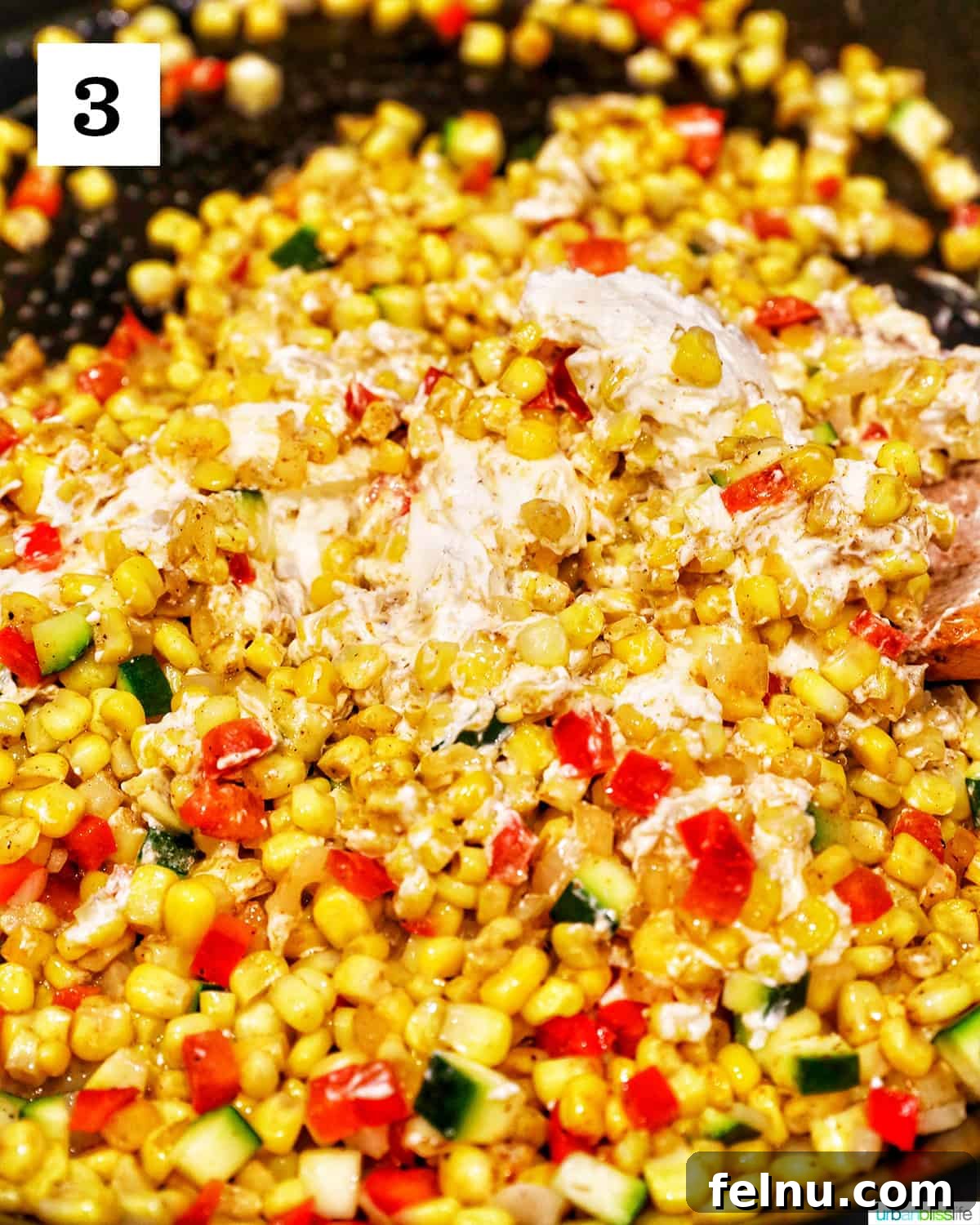 Creamy Kaleidoscope Corn 8 cream cheese added to corn and other veggies in a skillet.
