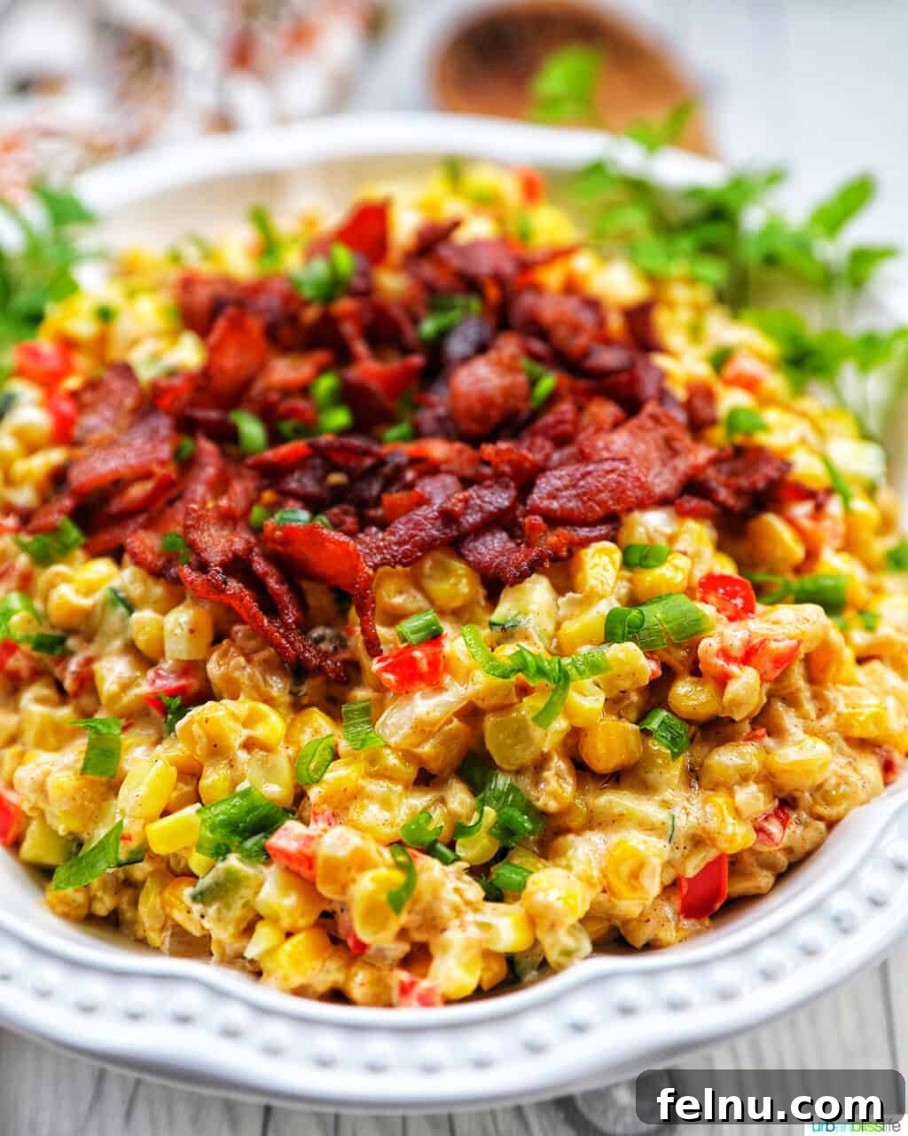 Creamy Kaleidoscope Corn 10 angled photo of creamy confetti corn with crispy bacon, green onions, peppers, in a white bowl.