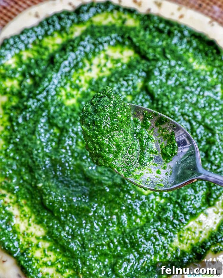 Effortless Spinach Pesto 4 A spoonful of fresh, vibrant spinach pesto sauce, highlighting its rich green color and smooth texture.