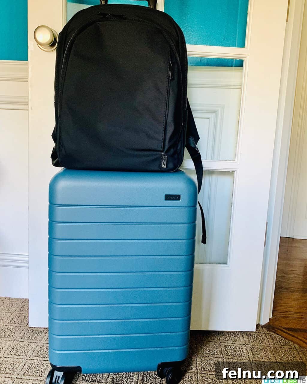 One Bag, One Week: Effortless Carry-On Packing 3 Black travel backpack resting on top of a blue hardside carry-on suitcase, illustrating a popular carry-on luggage combination.