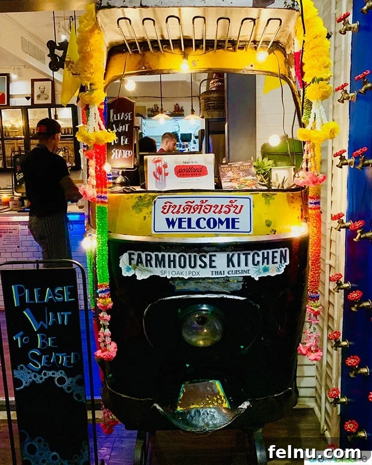 Portland's Farmhouse Table 2 Vibrantly colored Tuk Tuk, an iconic Thai three-wheeled vehicle, inside Farmhouse Kitchen Thai restaurant in Portland, beckoning diners into an authentic and lively atmosphere.