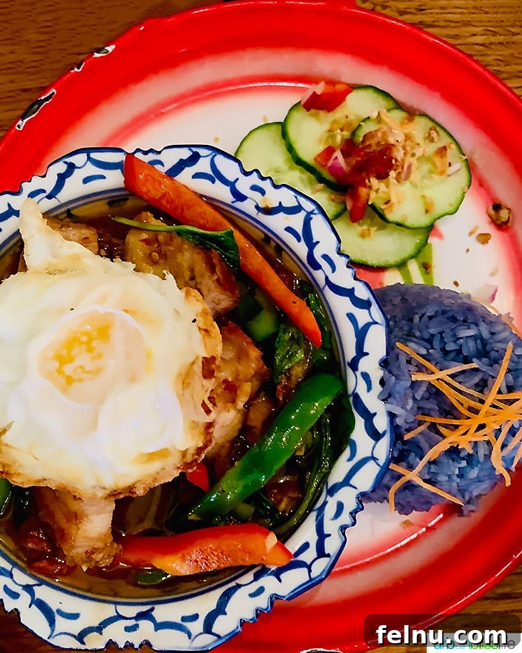 Portland's Farmhouse Table 10 Aromatic Pad Ka Pow, a classic Thai dish with crispy pork belly, fried egg, basil, and chili, served with blue rice and cucumber salad.