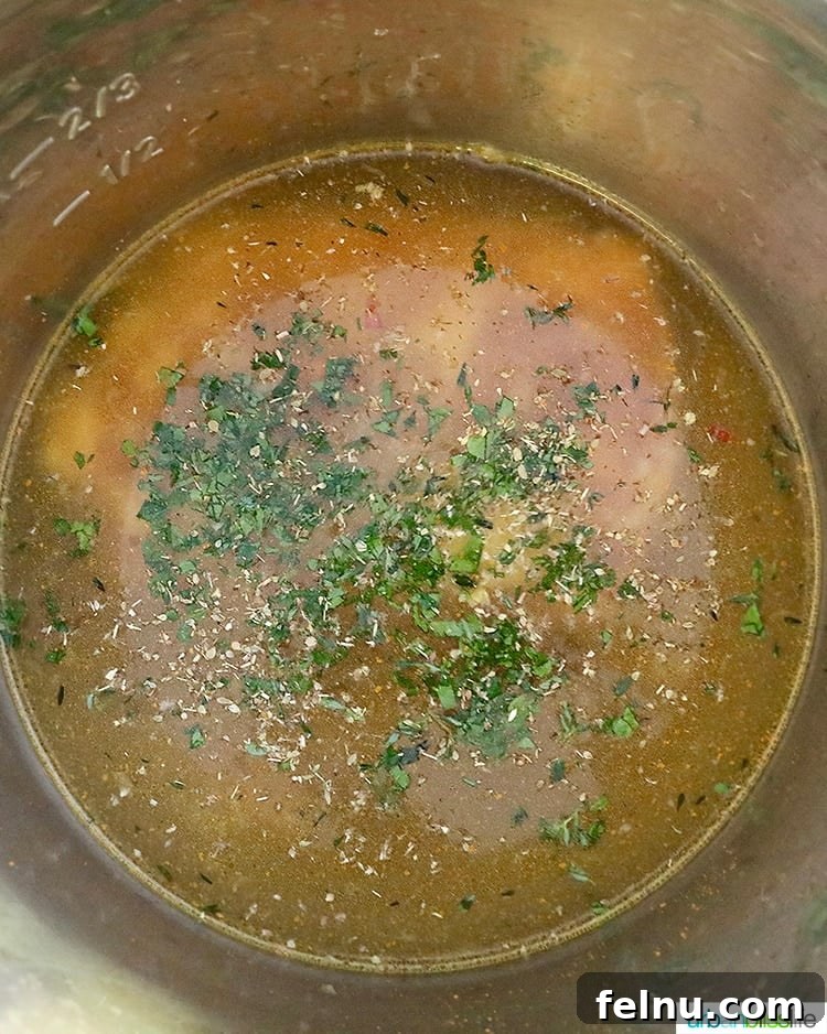 Deglazing the pot with chicken broth, adding frozen chicken, water, herbs, and turmeric before sealing the lid and cooking.