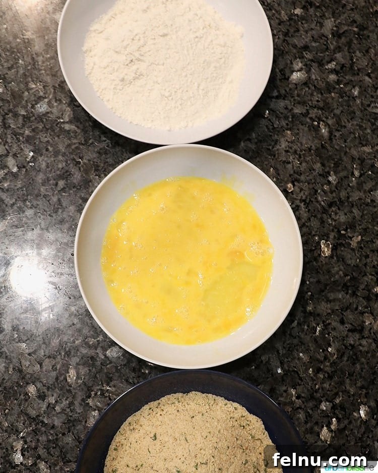 Three bowls of breading for chicken tenders