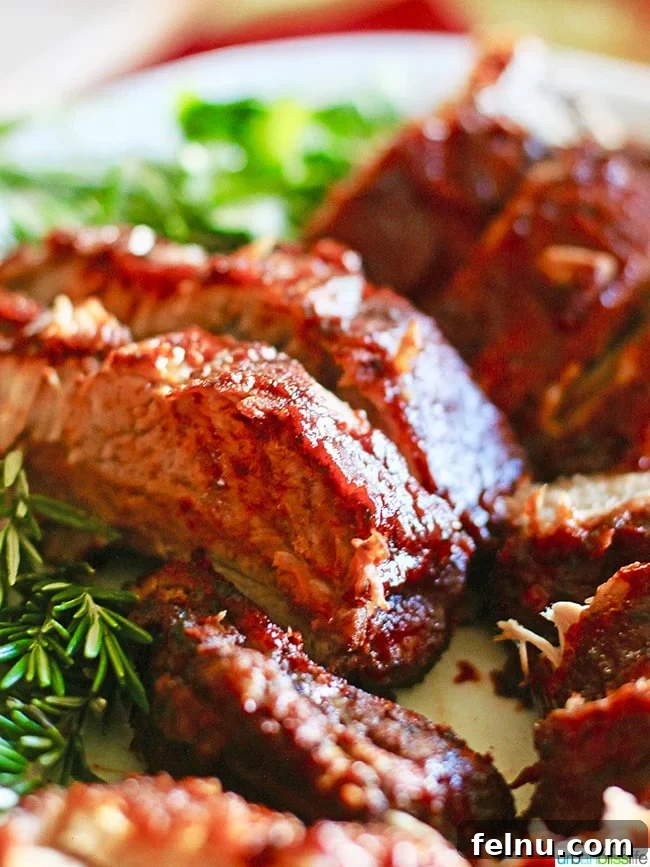 Sticky Sweet BBQ Perfection 7 A generous serving of Instant Pot BBQ Ribs, slathered with homemade sweet BBQ sauce, with a sprig of rosemary for garnish.