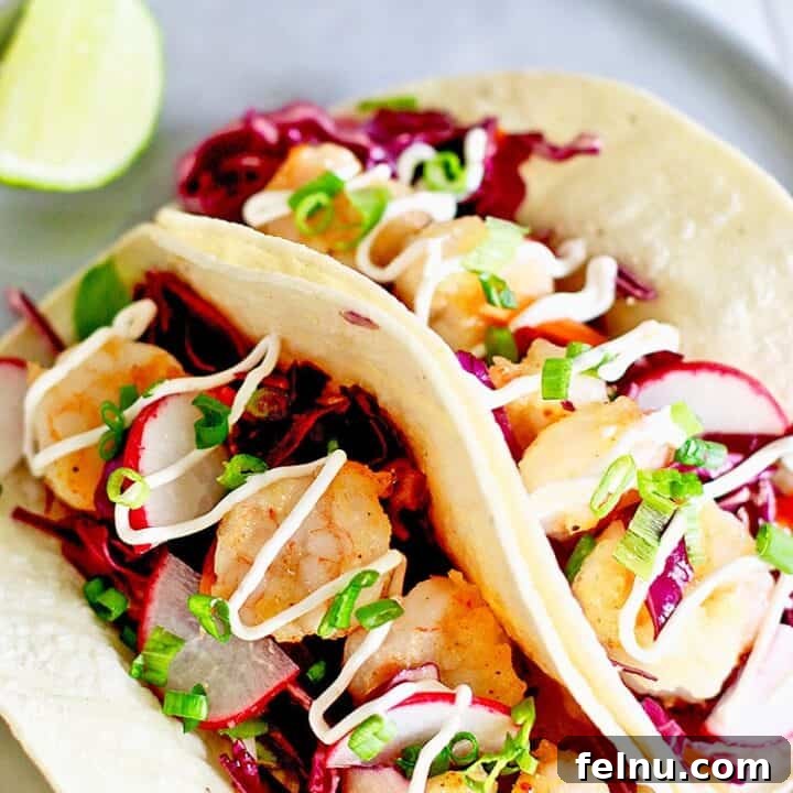 Easy Shrimp Tacos, two soft tortillas filled with seasoned shrimp, cabbage slaw, and a creamy sauce