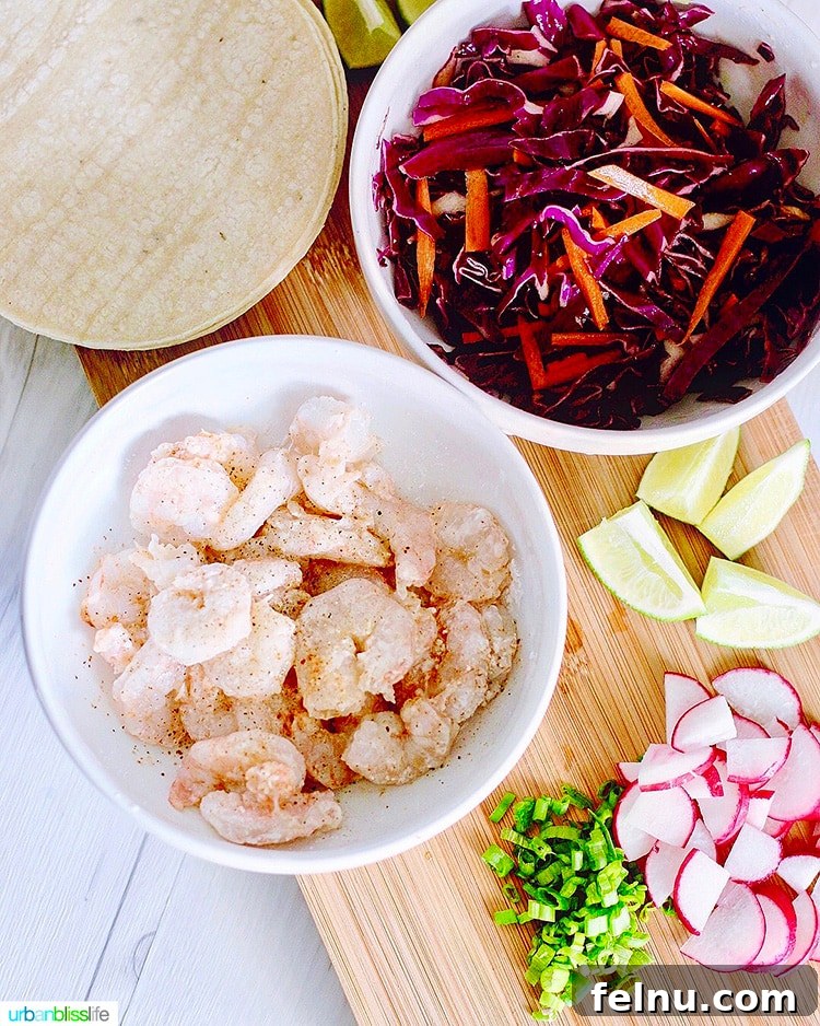 Ingredients laid out for Easy Shrimp Tacos, including shrimp, cabbage, limes, radishes, and seasoning