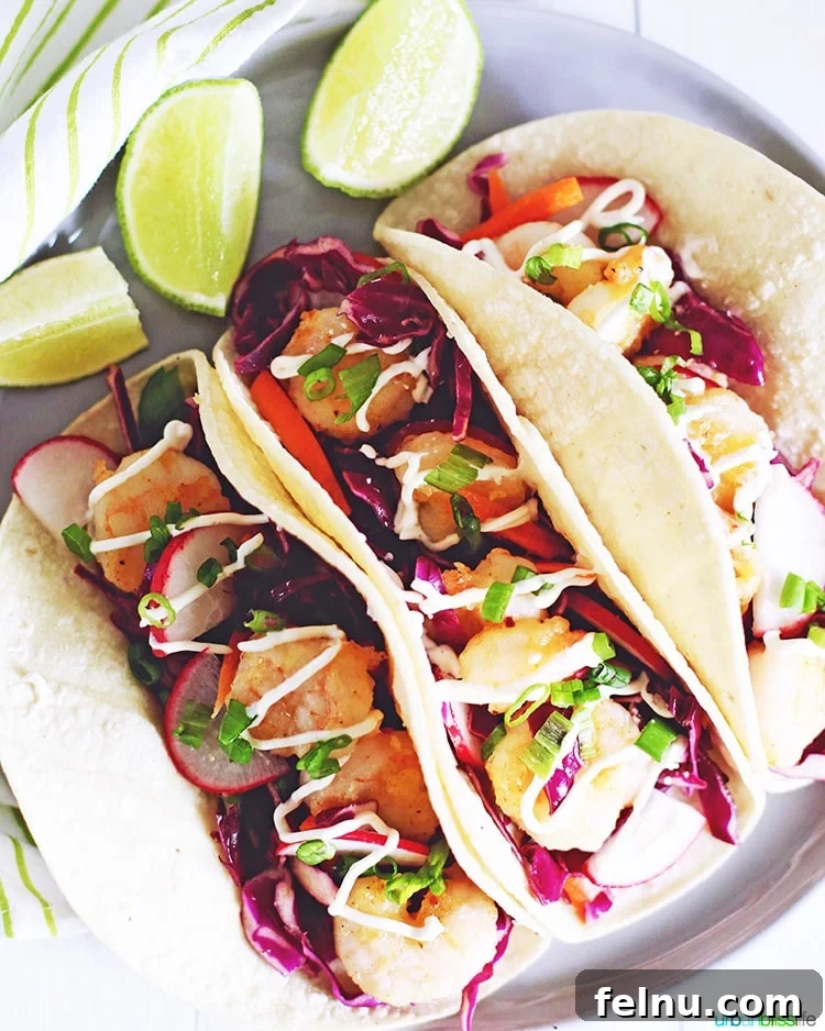 Three perfectly assembled shrimp tacos on a plate