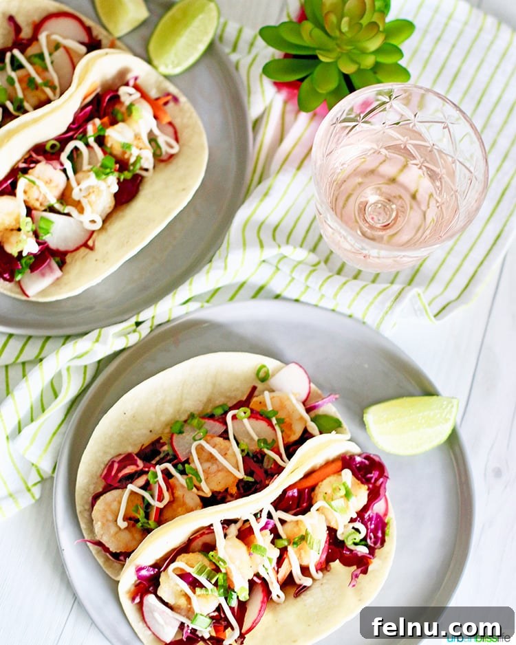 Flatlay of two plates of shrimp tacos with a glass of rosé wine and fresh ingredients