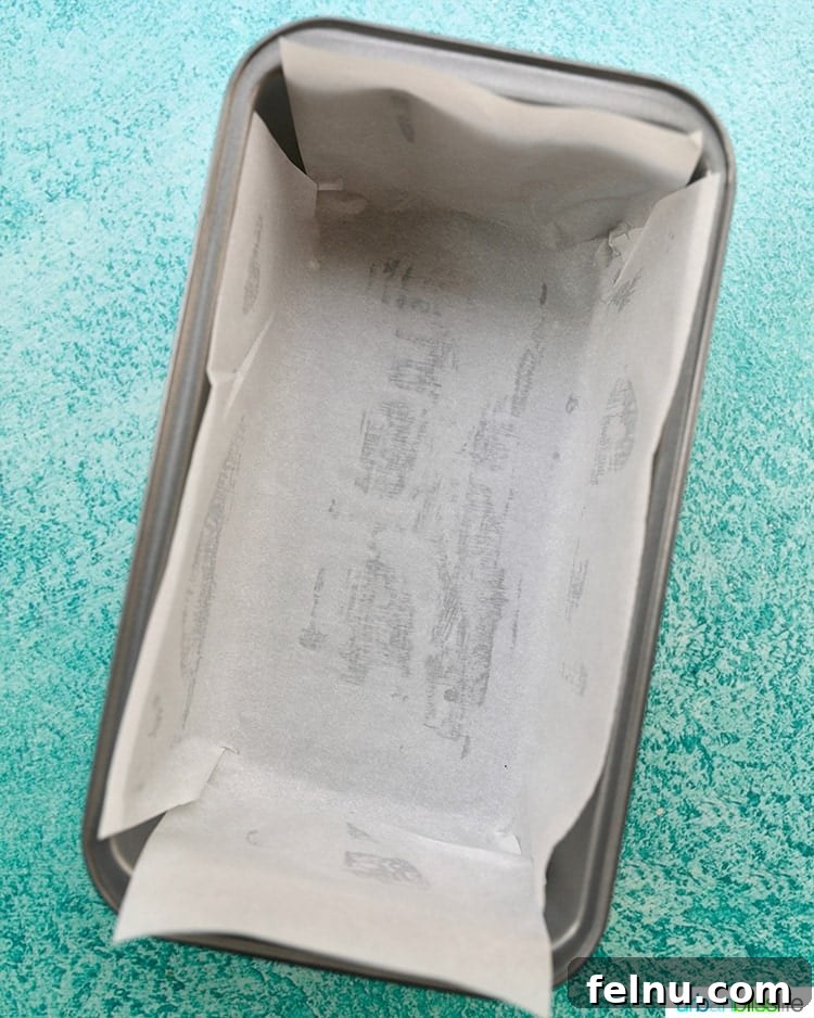 Pineapple Loaf 5 prepared loaf pan lined with parchment paper on a blue background.