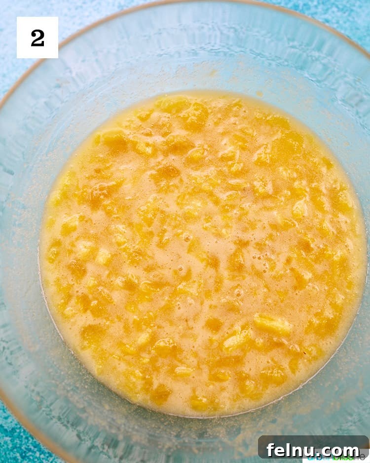 Pineapple Loaf 7 wet ingredients plus pineapple to make pineapple bread in a clear glass bowl on blue background.